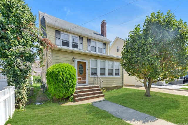 view of front facade featuring entry steps, a front yard, and fence