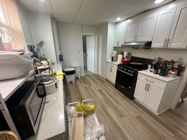 kitchen with light countertops, black gas stove, and white cabinetry