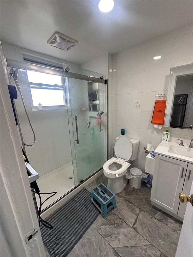 full bathroom featuring toilet, visible vents, vanity, tile walls, and a shower stall