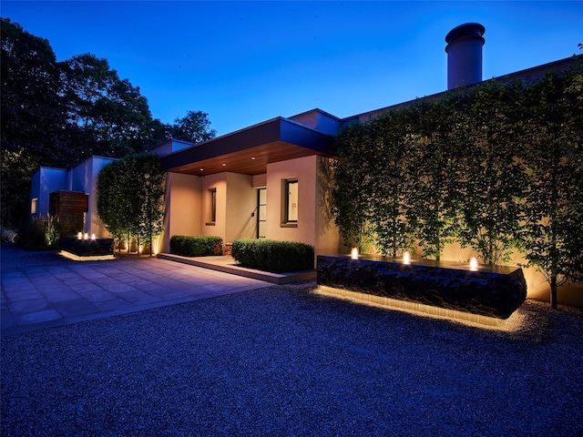 view of front of home with a patio area, a fire pit, and stucco siding