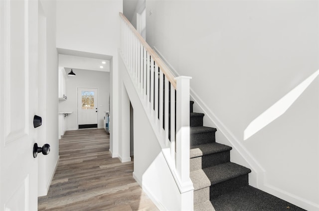 stairs featuring a high ceiling, baseboards, and wood finished floors