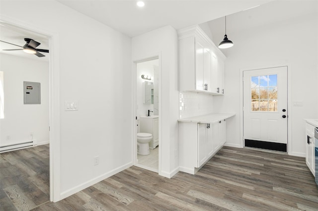 laundry room with electric panel, baseboards, baseboard heating, and wood finished floors