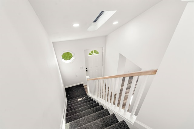 staircase with a skylight, baseboards, and recessed lighting