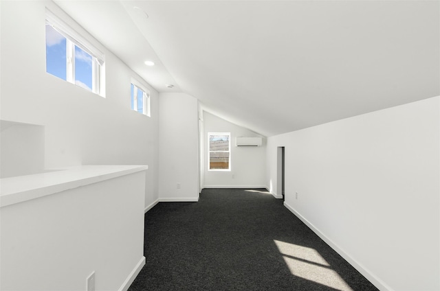 hallway featuring lofted ceiling, a wall unit AC, recessed lighting, baseboards, and dark carpet