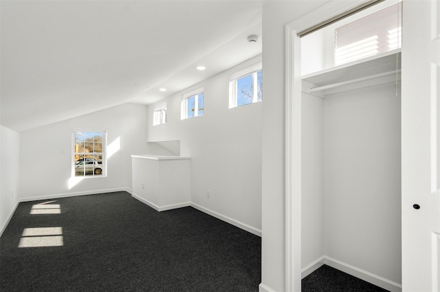 additional living space featuring lofted ceiling, baseboards, and dark colored carpet