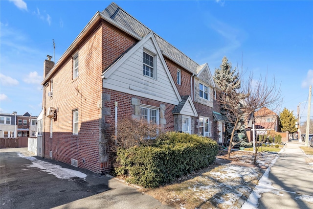 view of side of home featuring a residential view, brick siding, fence, and a chimney