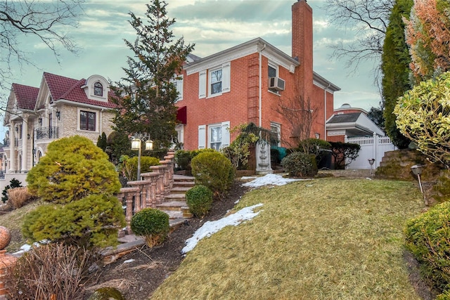 view of front facade featuring a front yard, fence, brick siding, and a chimney