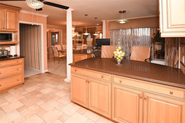 kitchen featuring dark countertops, stainless steel microwave, crown molding, decorative light fixtures, and decorative columns