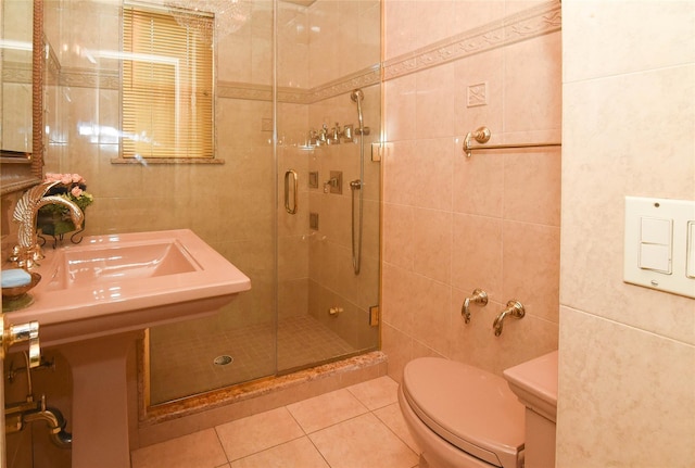 bathroom with tile patterned flooring, tile walls, toilet, and a stall shower