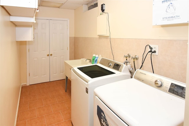 washroom featuring a wainscoted wall, washer and dryer, tile walls, light tile patterned floors, and laundry area