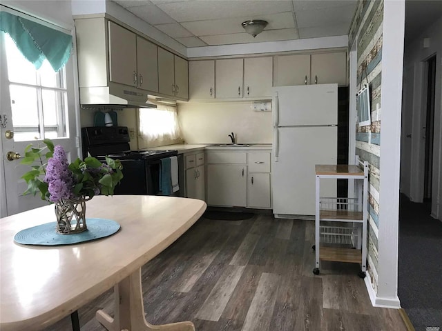 kitchen featuring a drop ceiling, electric range, light countertops, freestanding refrigerator, and dark wood-style floors