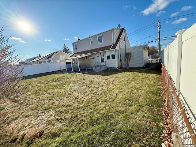 rear view of house with a fenced backyard and a lawn