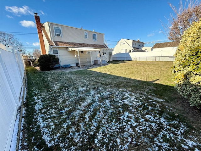 rear view of house with a fenced backyard, a yard, and a chimney