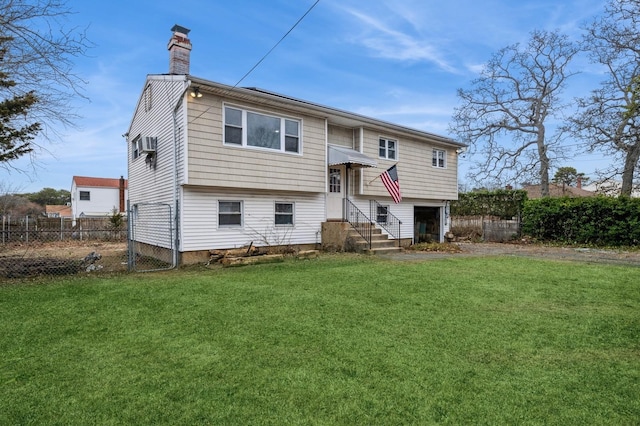 rear view of property featuring entry steps, fence, a chimney, and a lawn