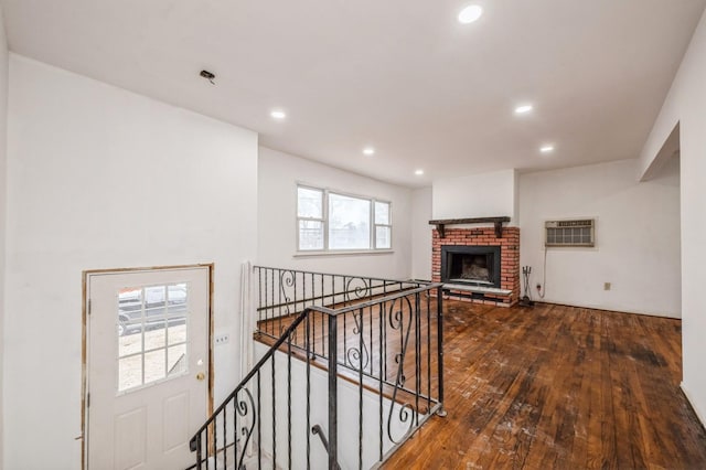 living room featuring recessed lighting, wood-type flooring, a wall unit AC, and a fireplace