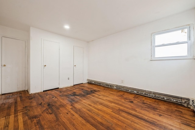 unfurnished bedroom with a baseboard heating unit and hardwood / wood-style flooring