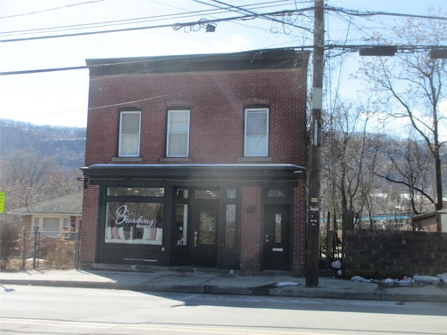 view of front facade with brick siding and fence