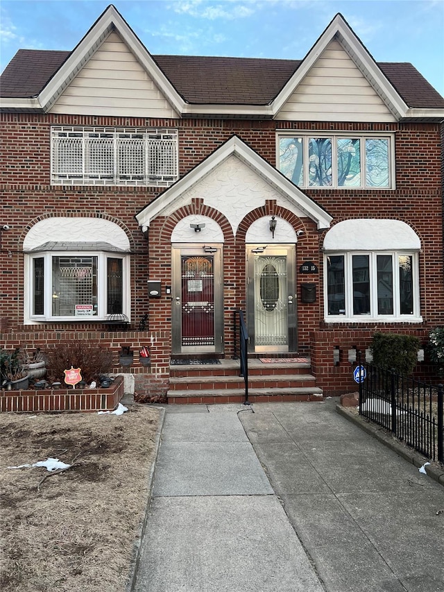 view of front of property featuring a shingled roof, entry steps, and brick siding