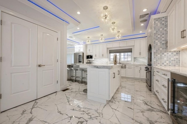 kitchen with beverage cooler, white cabinets, a breakfast bar area, a center island, and pendant lighting