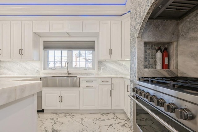 kitchen with extractor fan, high end stove, a sink, white cabinetry, and decorative backsplash