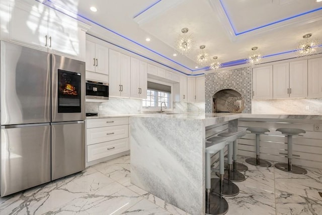 kitchen with a breakfast bar, refrigerator with glass door, and white cabinets