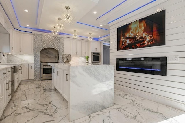 kitchen featuring white cabinetry, stainless steel oven, and a glass covered fireplace