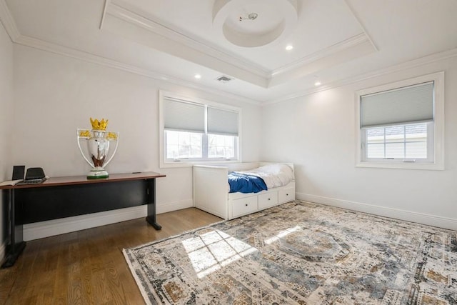 bedroom featuring ornamental molding, a raised ceiling, multiple windows, and wood finished floors