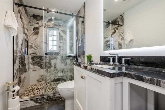 bathroom featuring toilet, vanity, and a marble finish shower