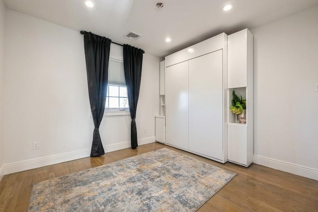 bedroom with baseboards, visible vents, and wood finished floors