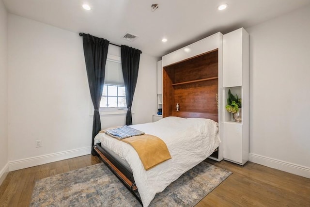 bedroom with recessed lighting, visible vents, baseboards, and wood finished floors