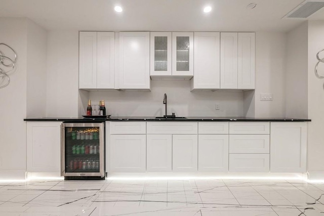 kitchen featuring glass insert cabinets, wine cooler, white cabinets, and dark countertops