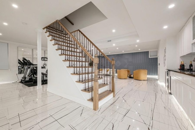 stairs with recessed lighting, marble finish floor, a raised ceiling, and wine cooler