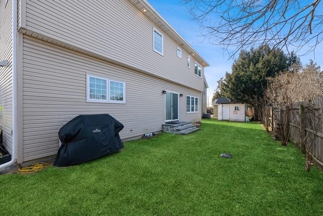 rear view of house with fence, a lawn, and an outbuilding