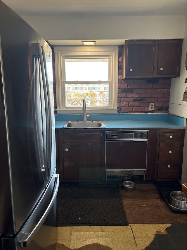 kitchen featuring a sink, light countertops, dark brown cabinets, freestanding refrigerator, and dishwasher