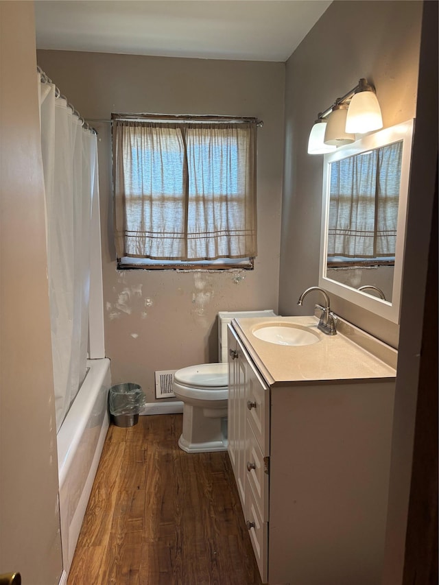 bathroom featuring visible vents, toilet, shower / tub combo with curtain, wood finished floors, and vanity