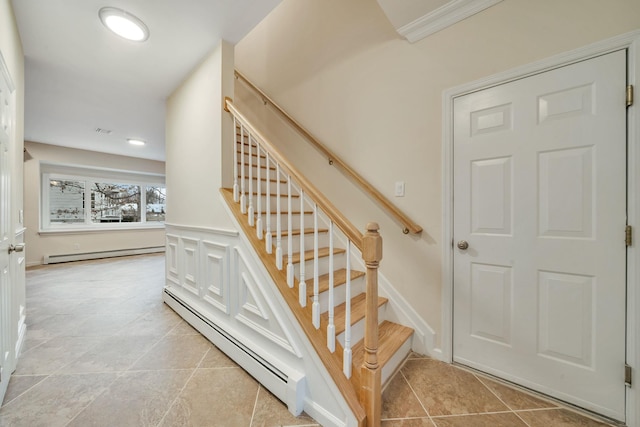 stairway featuring a baseboard heating unit, a wainscoted wall, visible vents, and a decorative wall