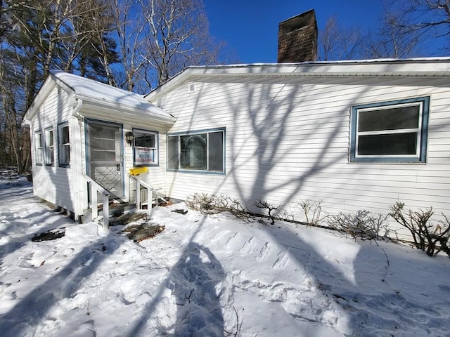 view of snowy exterior featuring a chimney