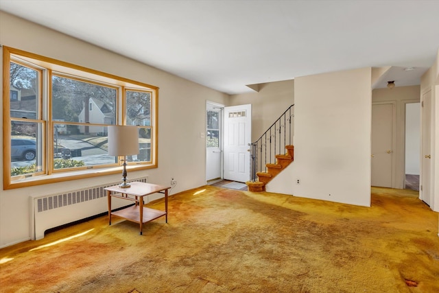 carpeted entrance foyer with stairs and radiator heating unit