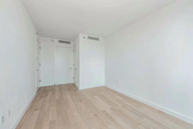 unfurnished room with light wood-style flooring, visible vents, and baseboards