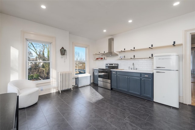 kitchen with wall chimney range hood, stainless steel electric range, freestanding refrigerator, radiator, and open shelves