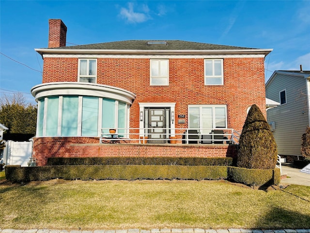 rear view of property featuring a chimney, a lawn, and brick siding