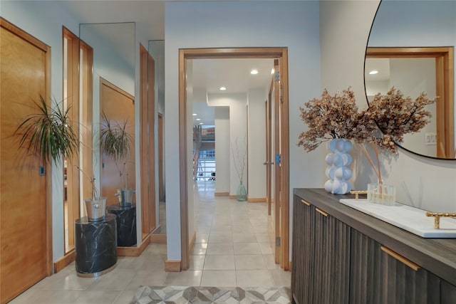 hall featuring recessed lighting, baseboards, and light tile patterned flooring