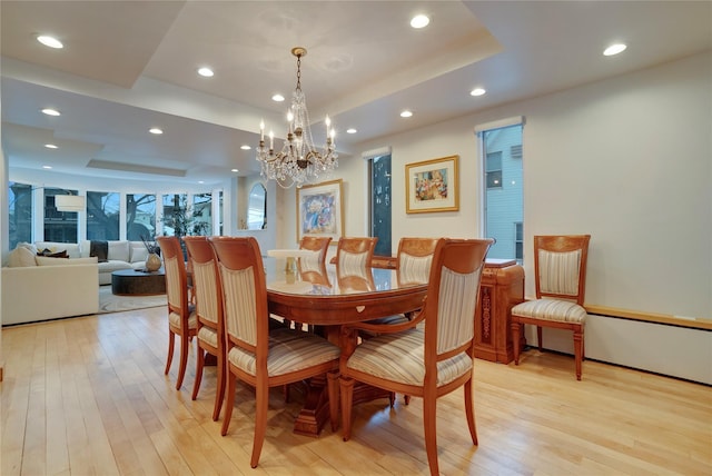 dining space with light wood finished floors, a tray ceiling, and recessed lighting