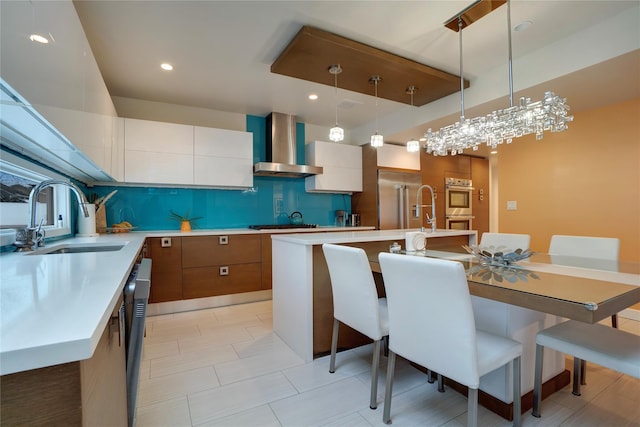 kitchen featuring wall chimney exhaust hood, modern cabinets, light countertops, and a sink