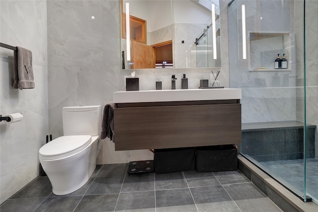 bathroom with tile walls, toilet, a stall shower, vanity, and tile patterned floors