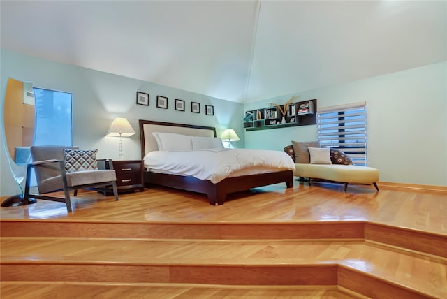 bedroom with high vaulted ceiling and wood finished floors