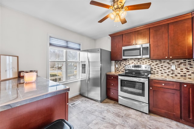 kitchen with stainless steel appliances, tasteful backsplash, visible vents, and a ceiling fan