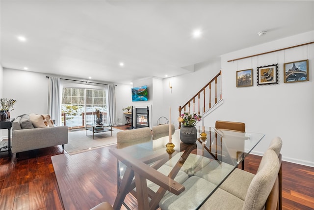 dining area featuring baseboards, stairs, recessed lighting, wood finished floors, and a glass covered fireplace