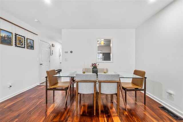 dining room with dark wood-style floors, visible vents, and baseboards