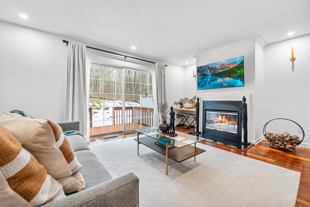 living area with a glass covered fireplace, recessed lighting, wood finished floors, and visible vents